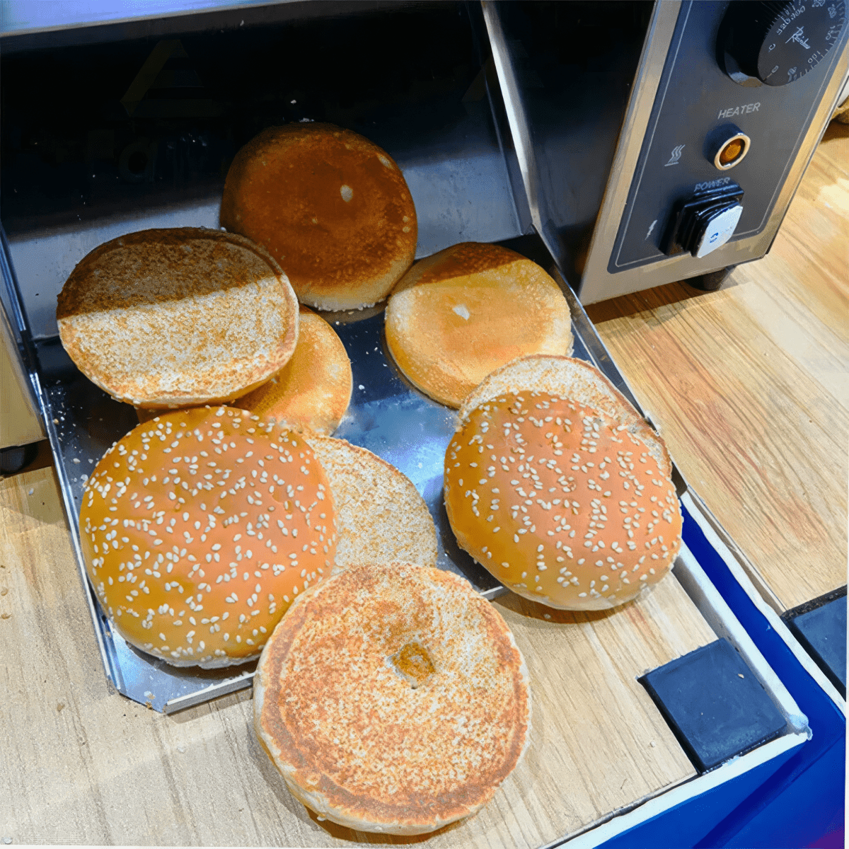 Golden brown caramelized hamburger buns toasted by electric vertical conveyor toaster