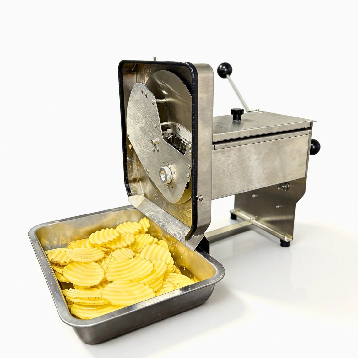 Side profile of the heavy-duty crinkle cut french fry machine showing the output chute and a full tray of freshly cut wavy potato slices.