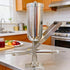 Manual cream filler shown in upright and horizontal positions on a kitchen table, sturdy stainless steel base.