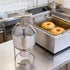Making fresh donuts using a manual batter dispenser positioned over a commercial electric fryer